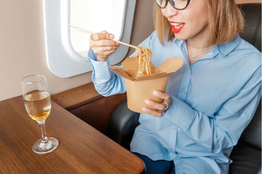 Woman eating greasy food on plane.